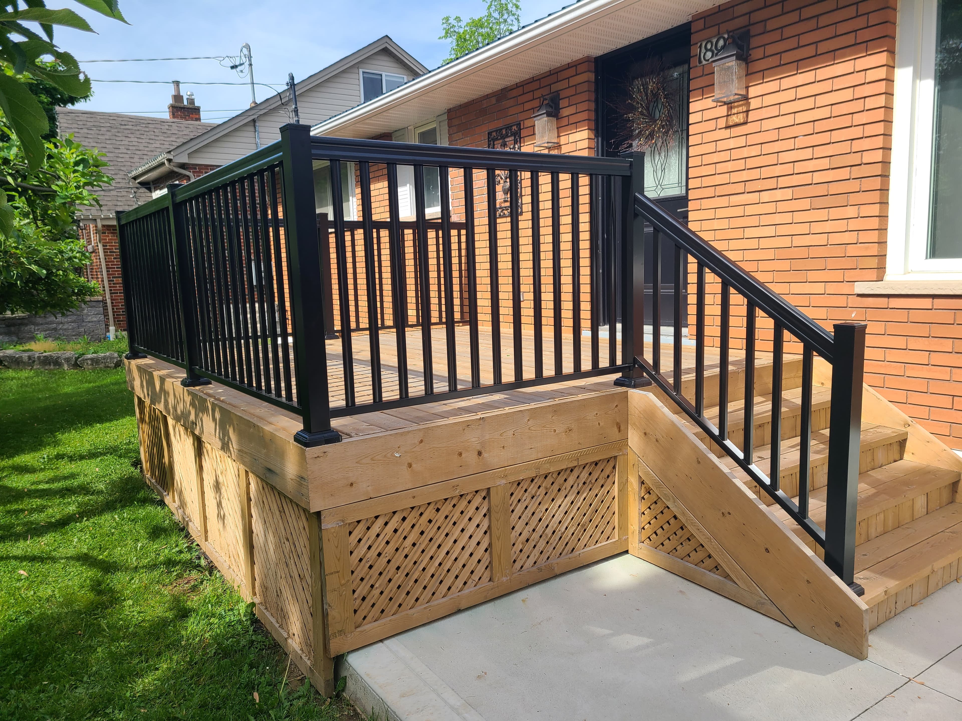 Black aluminum railing installed along a concrete front walkway
